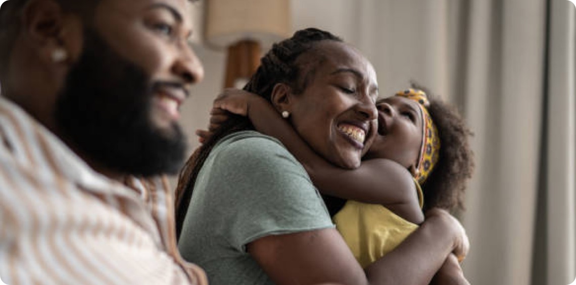 Child hugging woman with man also in photo