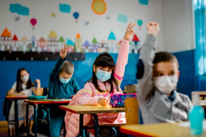 Children in classroom raising hands.