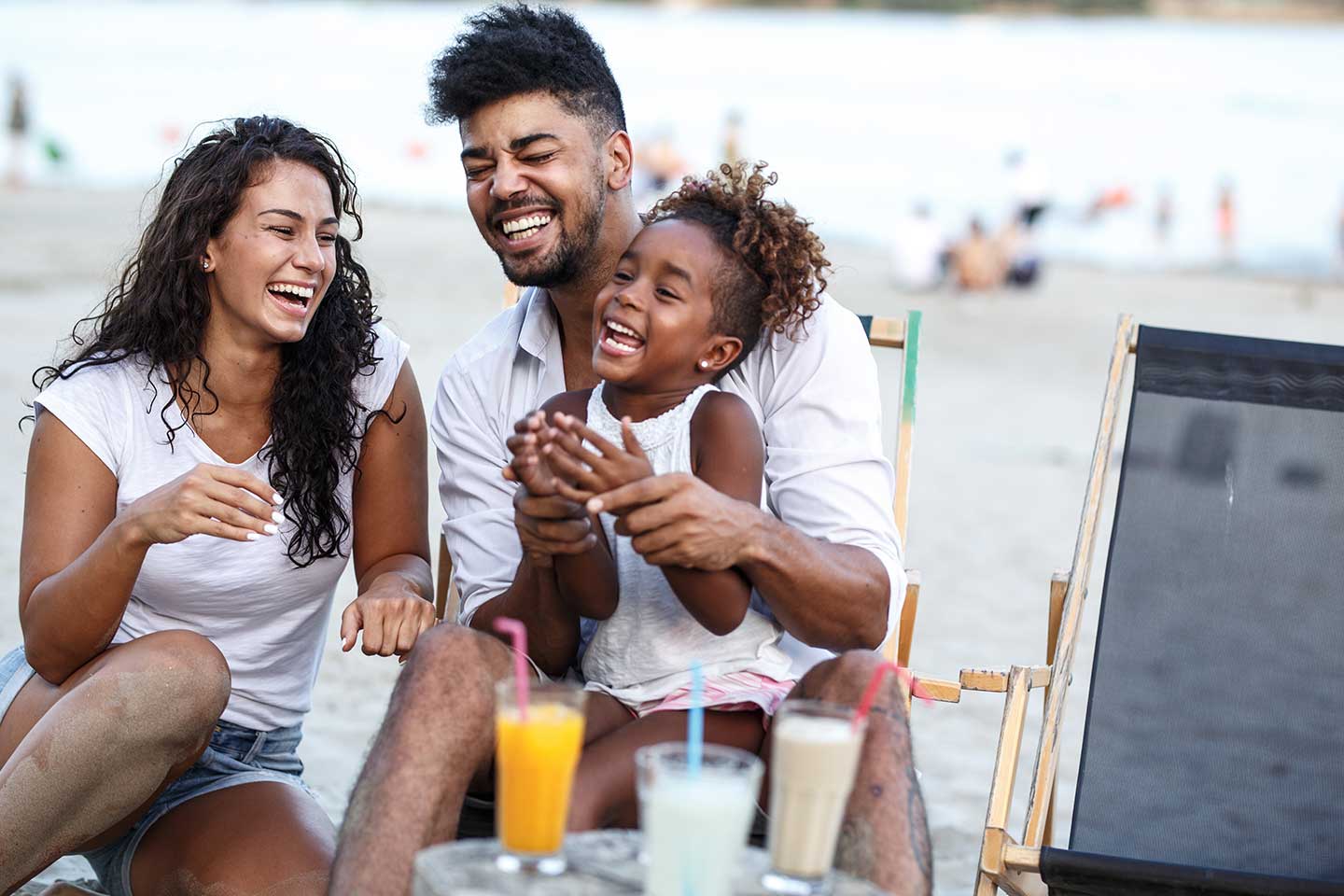 Family with child laughing at the beach.