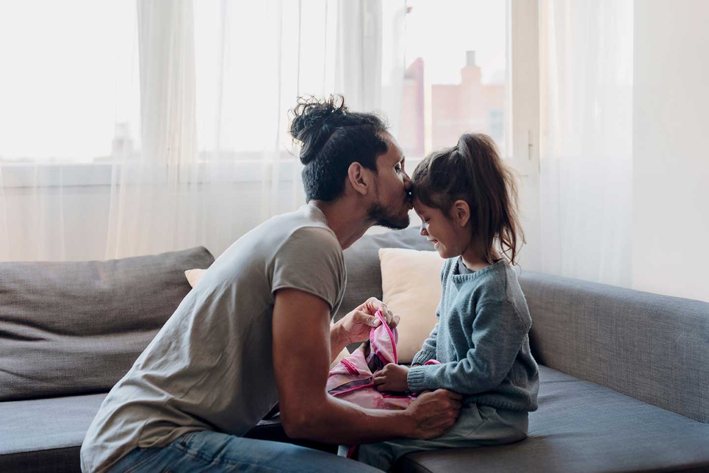 Father kissing daughter's forehead.