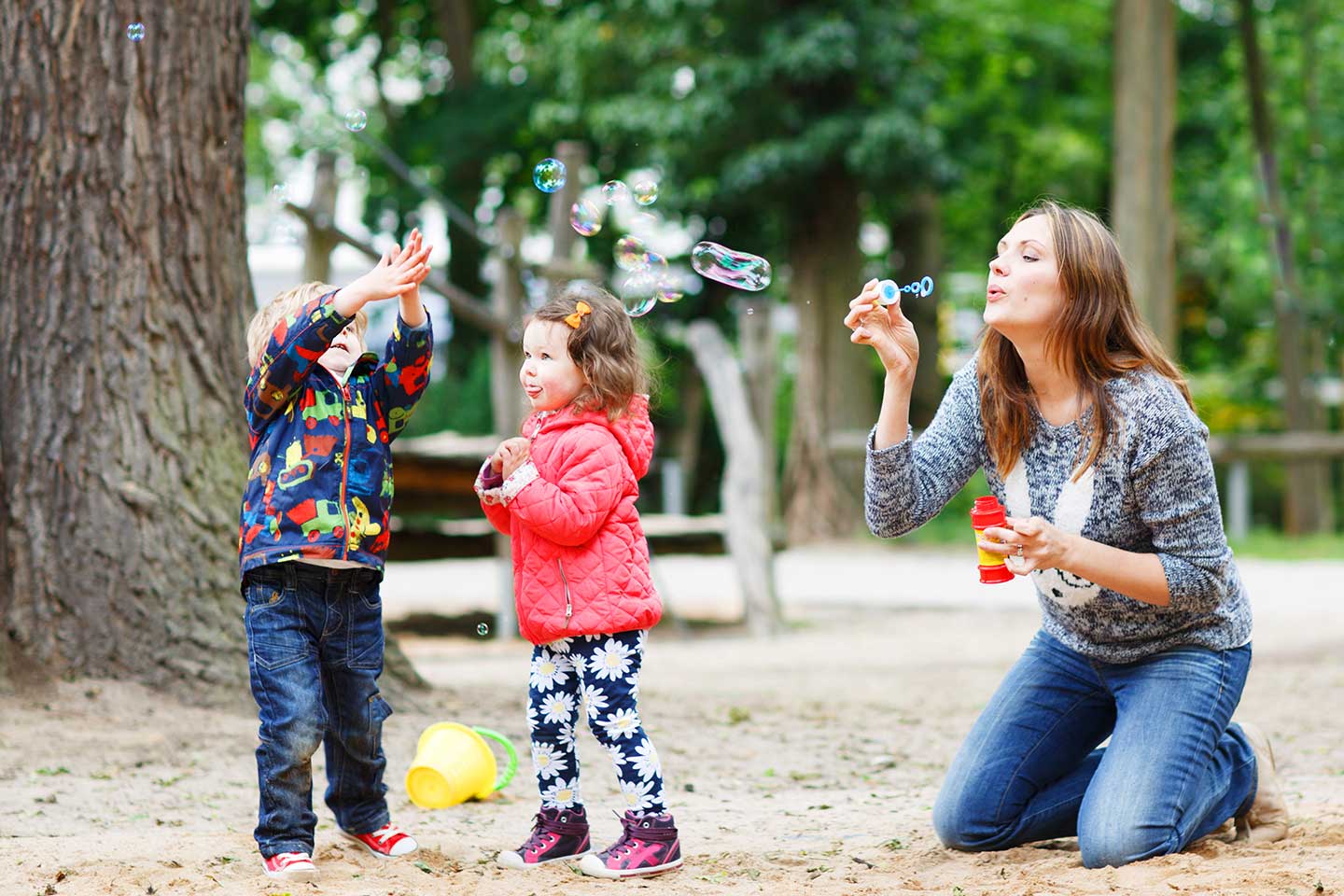 Woman blowing bubbles with children.