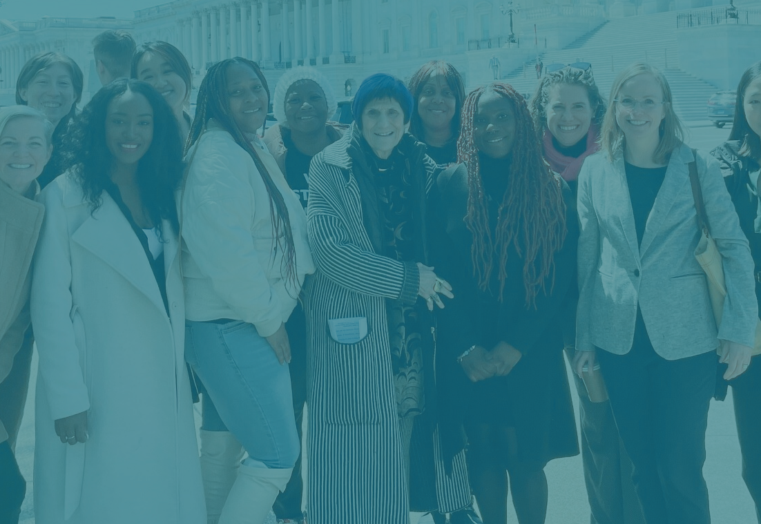 Photo of a diverse group of people standing and smiling in front of the U.S. Capitol building in the winter